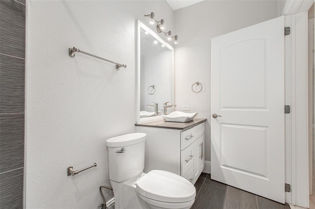 4719 Junius Street, Unit 3 Dallas, TX 75246 - Photo 23 of 38 a bathroom with a granite countertop toilet sink and mirror