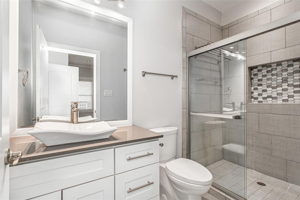 4719 Junius Street, Unit 3 Dallas, TX 75246 - Photo 27 of 38 a bathroom with a granite countertop sink a toilet a mirror and shower
