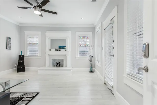 a view of a livingroom with a fireplace a ceiling fan and windows