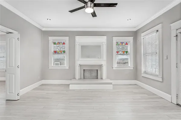 a view of livingroom with a fireplace a ceiling fan and windows