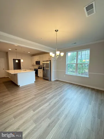 a view of a room with wooden floor and kitchen view