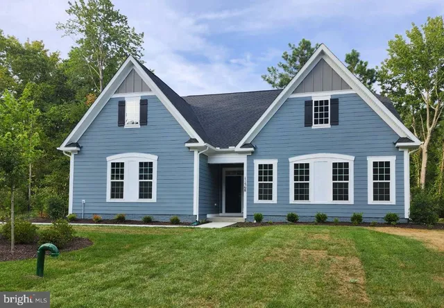 a view of a yard in front of a house with plants and large tree