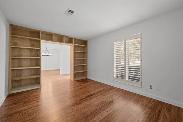 a view of an empty room with window and wooden floor