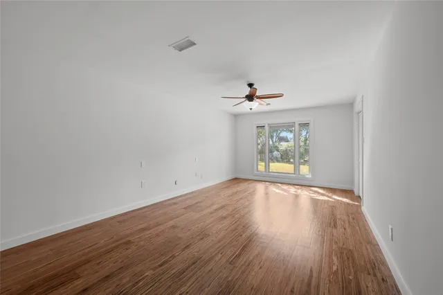 a view of a room with wooden floor a chandelier and windows
