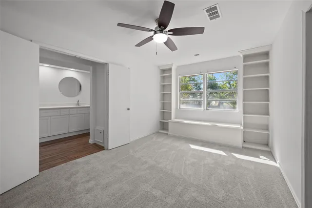an empty room with a chandelier fan and windows