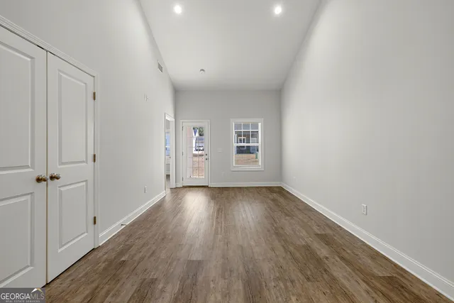 an empty room with wooden floor and windows