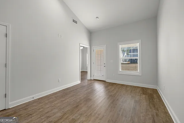 an empty room with wooden floor and windows