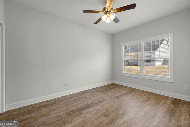 a view of empty room with wooden floor and fan
