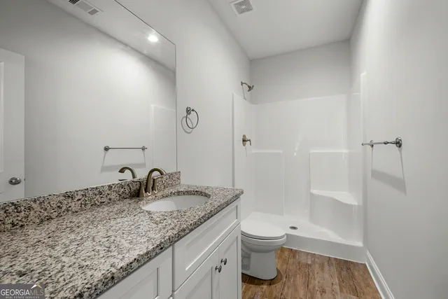 a bathroom with a granite countertop sink a toilet and shower