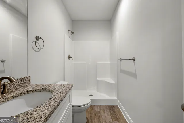 a bathroom with a granite countertop sink a toilet and shower