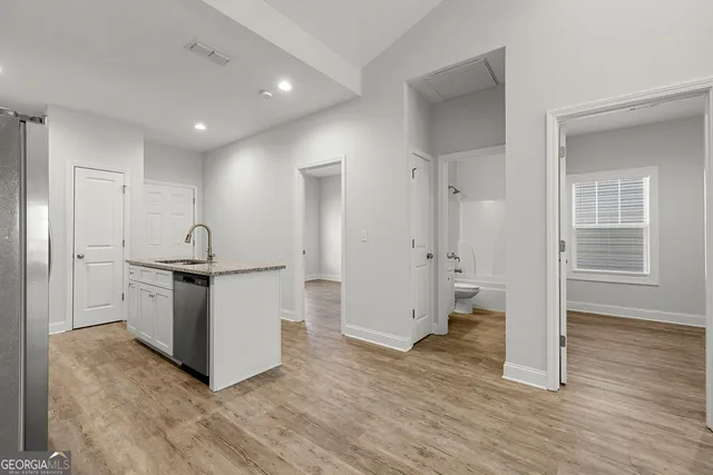 a view of a kitchen with stainless steel appliances wooden floor and chair
