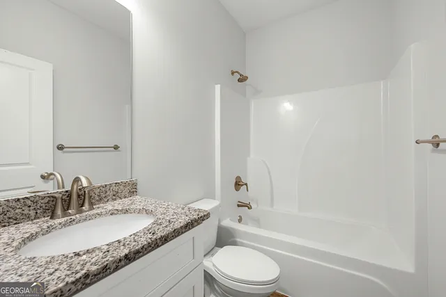 a bathroom with a granite countertop sink a toilet and bathtub