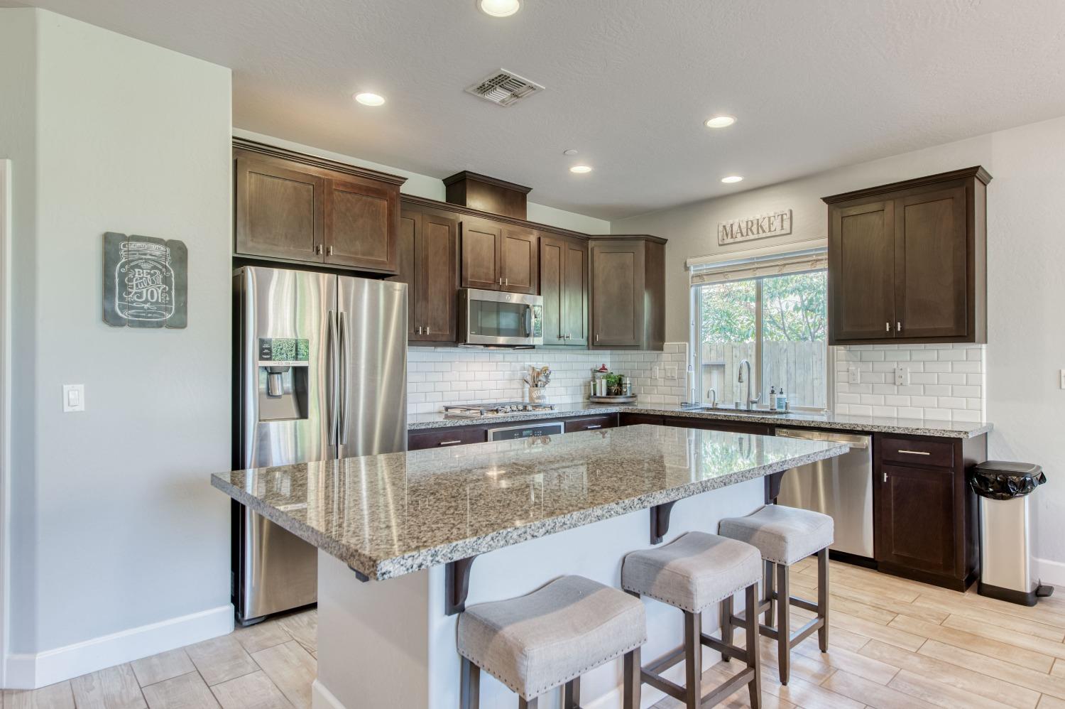 3539 Taylor Lane Clovis, CA 93619 - Photo 8 of 33 a kitchen with kitchen island granite countertop a refrigerator oven a sink a dining table and chairs
