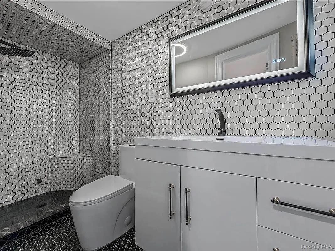 643 Decatur Street, Unit 1 Brooklyn, NY 11233 - Photo 10 of 27 a bathroom with a toilet sink and mirror