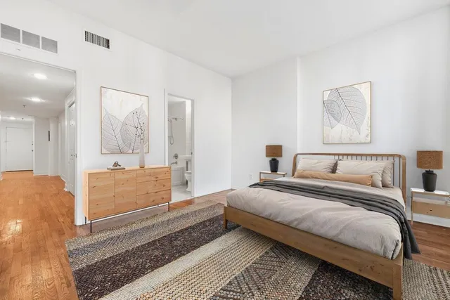 a spacious bedroom with a bed a mirror and lamp