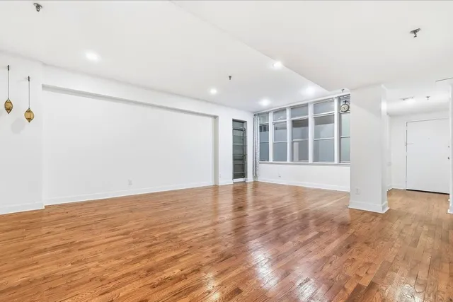a view of an empty room with wooden floor and windows