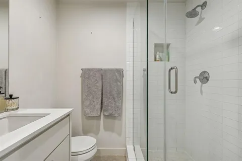 a bathroom with a granite countertop sink a toilet and shower