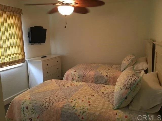 a bedroom with a bed and a flat tv screen on dresser