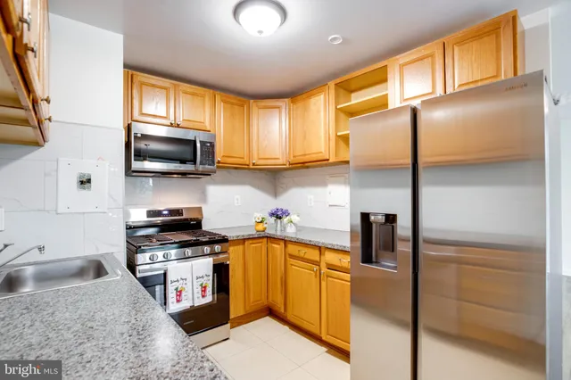 a kitchen with stainless steel appliances granite countertop a sink a stove cabinets counter space and a window