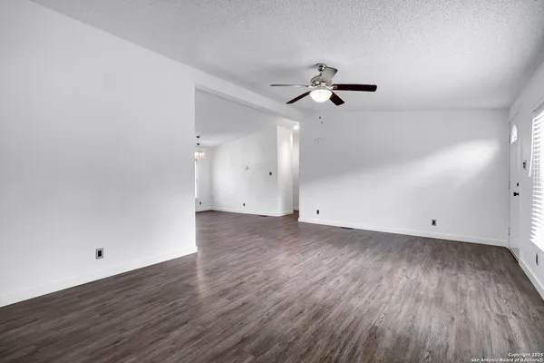 an empty room with wooden floor ceiling fan and window