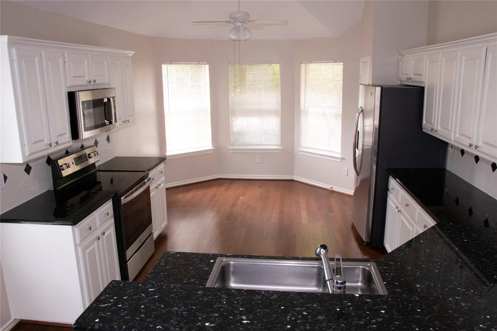 10702 Huntington Road Frisco, TX 75035 - Photo 6 of 23 a kitchen with granite countertop a stove a sink and a microwave