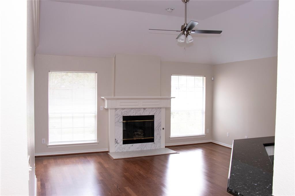 10702 Huntington Road Frisco, TX 75035 - Photo 8 of 23 a view of a livingroom with a fireplace a ceiling fan and windows