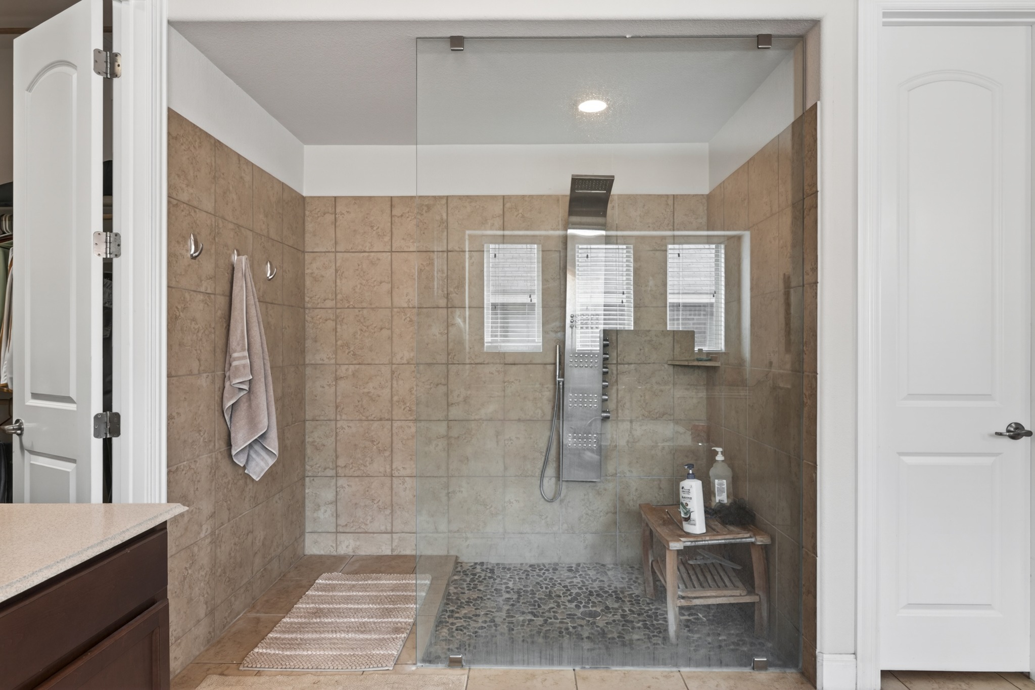 1017 Tabernash Leander, TX 78641 - Photo 24 of 38 Expansive walk-in shower featuring glass enclosure, tiled walls, pebble-finish flooring, a built-in bench, and multiple shower heads
