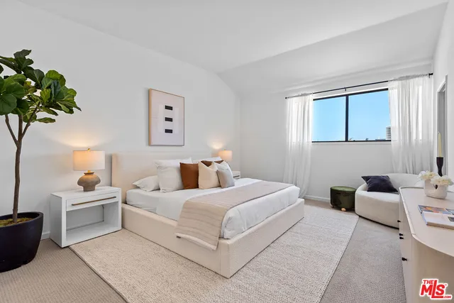 a bedroom with a bed couch and a potted plant