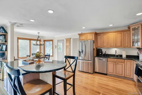 a kitchen with stainless steel appliances granite countertop a stove a sink a refrigerator dining table and chairs