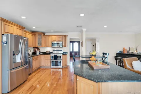 a kitchen with stainless steel appliances granite countertop a refrigerator a stove and a sink with wooden floors