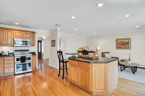a view of a kitchen with kitchen island a stove a refrigerator a dining table and chairs with wooden floor