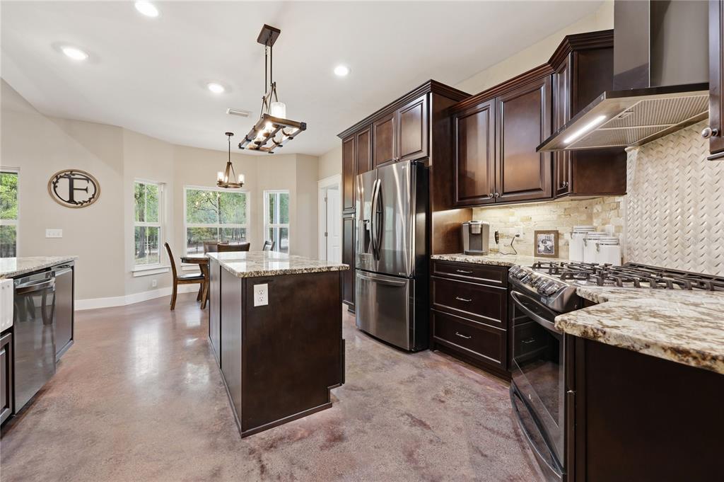357 Southwest Conestoga Way Fort White, FL 32038 - Photo 12 of 44 a kitchen with stainless steel appliances granite countertop a refrigerator a stove top oven a sink dishwasher and wooden cabinets