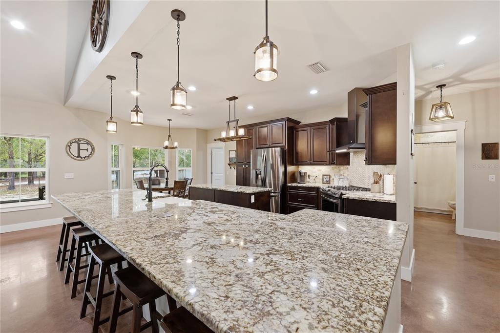 357 Southwest Conestoga Way Fort White, FL 32038 - Photo 14 of 44 a kitchen with stainless steel appliances kitchen island granite countertop a refrigerator a oven a sink a dining table and chairs with wooden floor