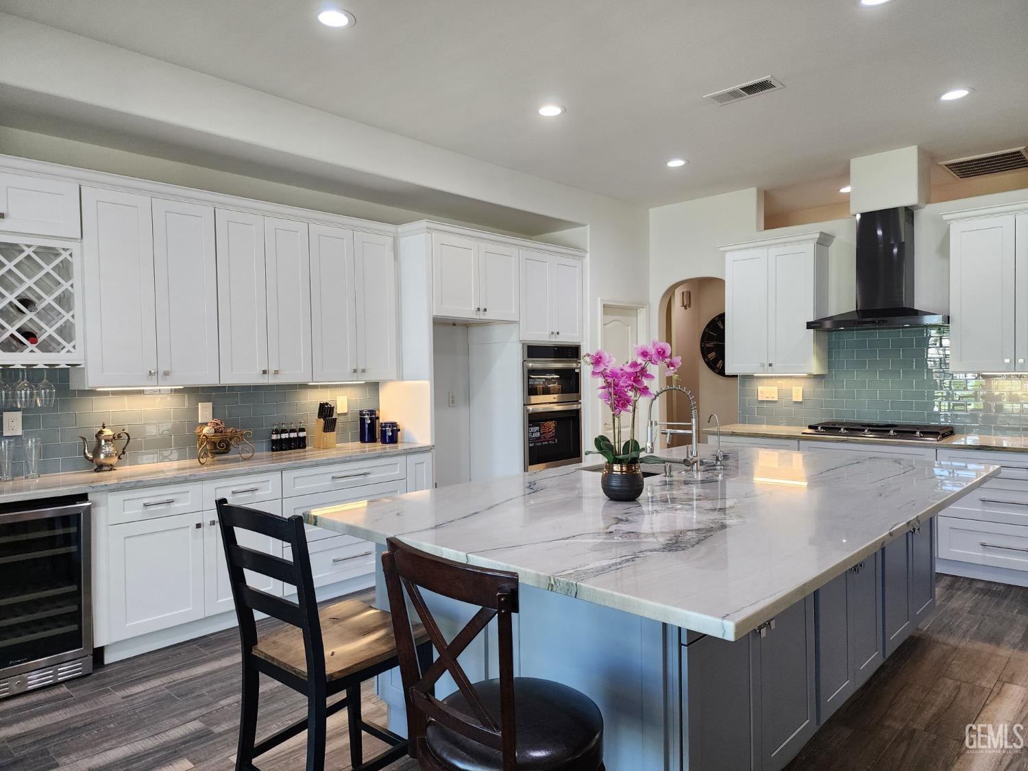 a kitchen with stainless steel appliances kitchen island granite countertop a table chairs in it and white cabinets