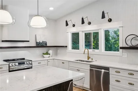 a large kitchen with kitchen island a large counter space a sink appliances and a view of living room