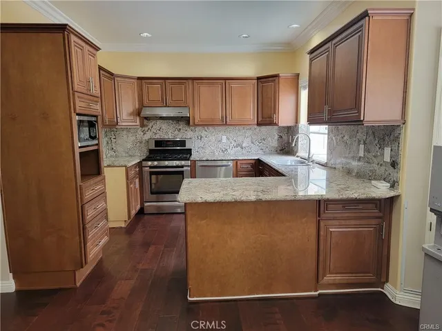 a kitchen with kitchen island granite countertop wooden floors and stainless steel appliances