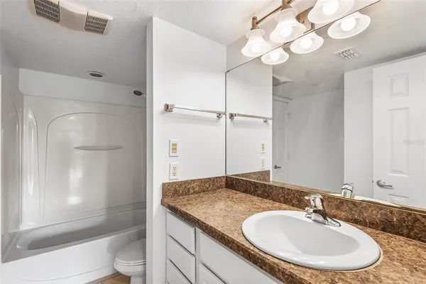 a bathroom with a granite countertop sink a toilet and shower