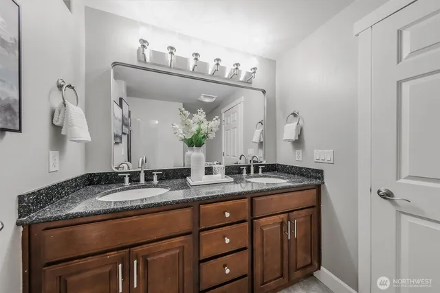 a bathroom with a granite countertop sink double vanity and mirror