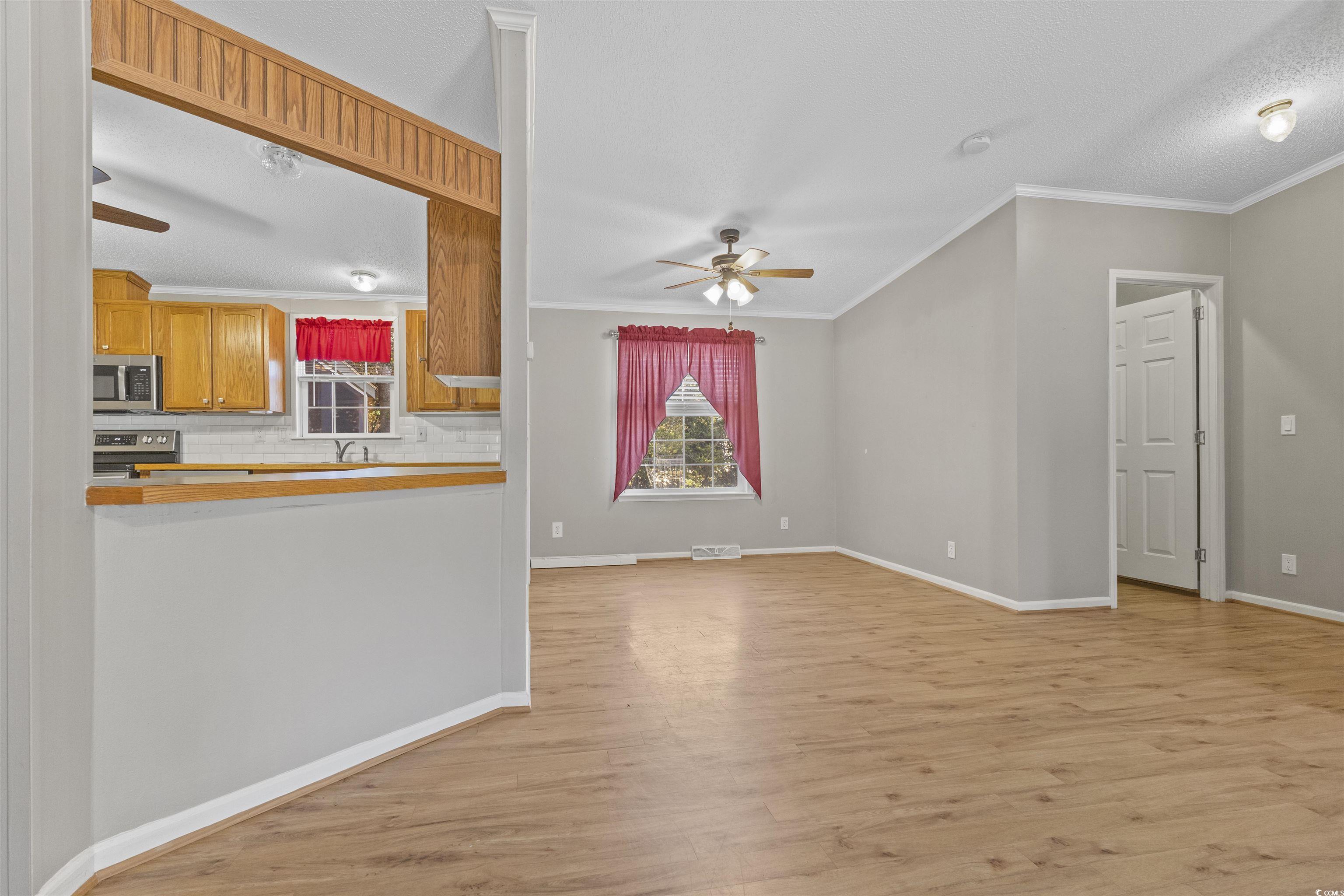 48 Talon Circle Murrells Inlet, SC 29576 - Photo 11 of 28 Kitchen with a ceiling fan, light wood-type flooring, decorative backsplash, ornamental molding, and brown cabinetry