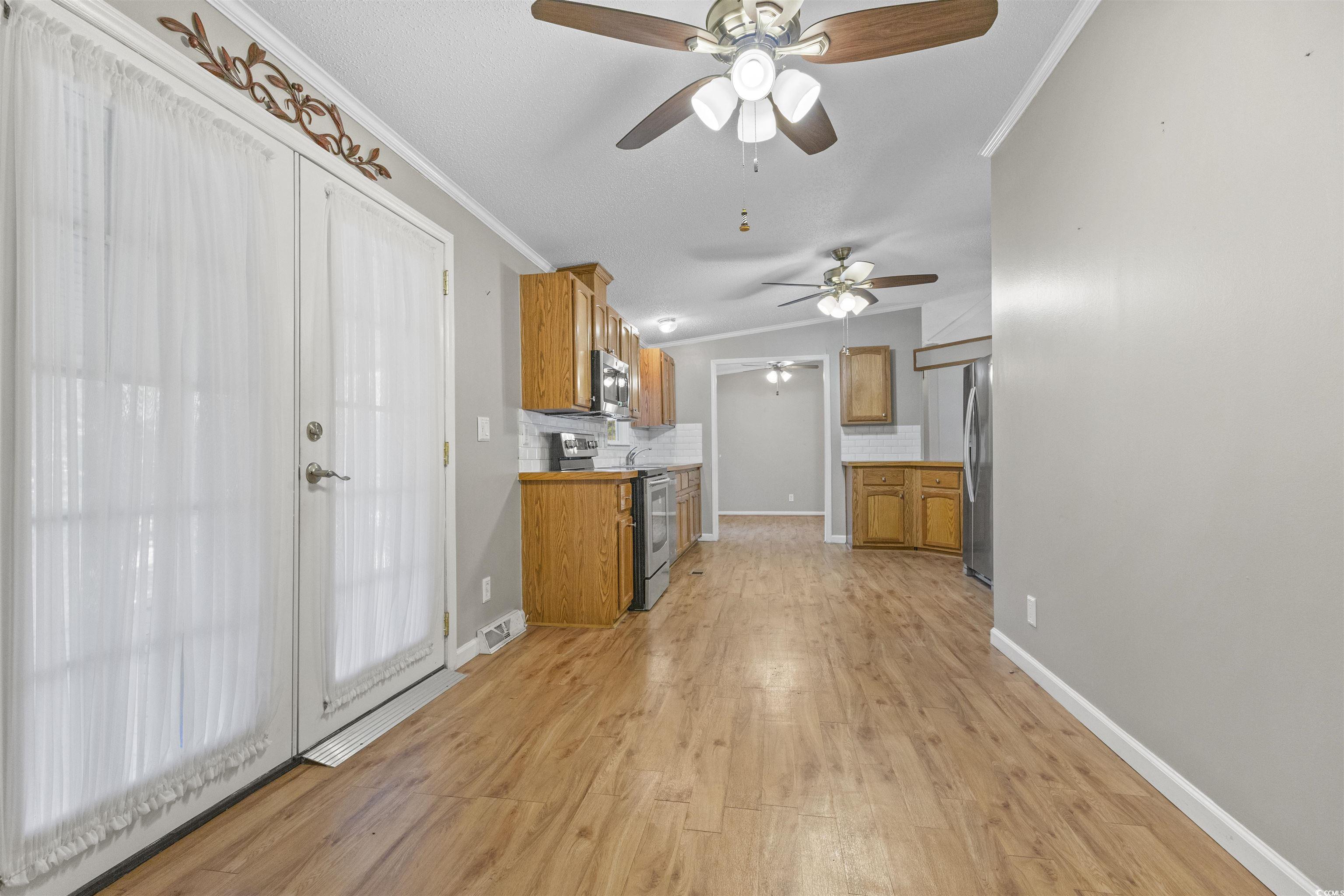 48 Talon Circle Murrells Inlet, SC 29576 - Photo 12 of 28 Kitchen with light countertops, appliances with stainless steel finishes, brown cabinets, backsplash, and crown molding