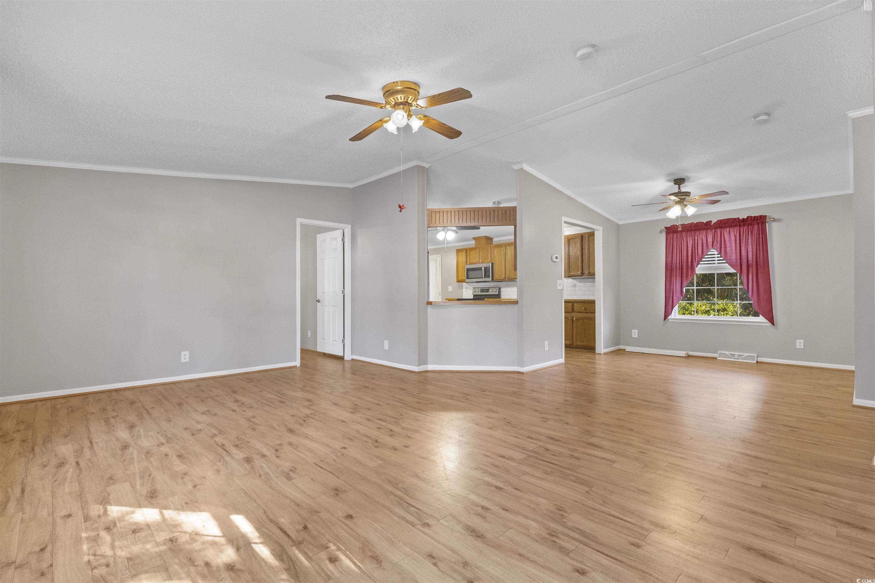 48 Talon Circle Murrells Inlet, SC 29576 - Photo 6 of 28 Unfurnished living room with lofted ceiling, ornamental molding, light wood-style floors, and ceiling fan