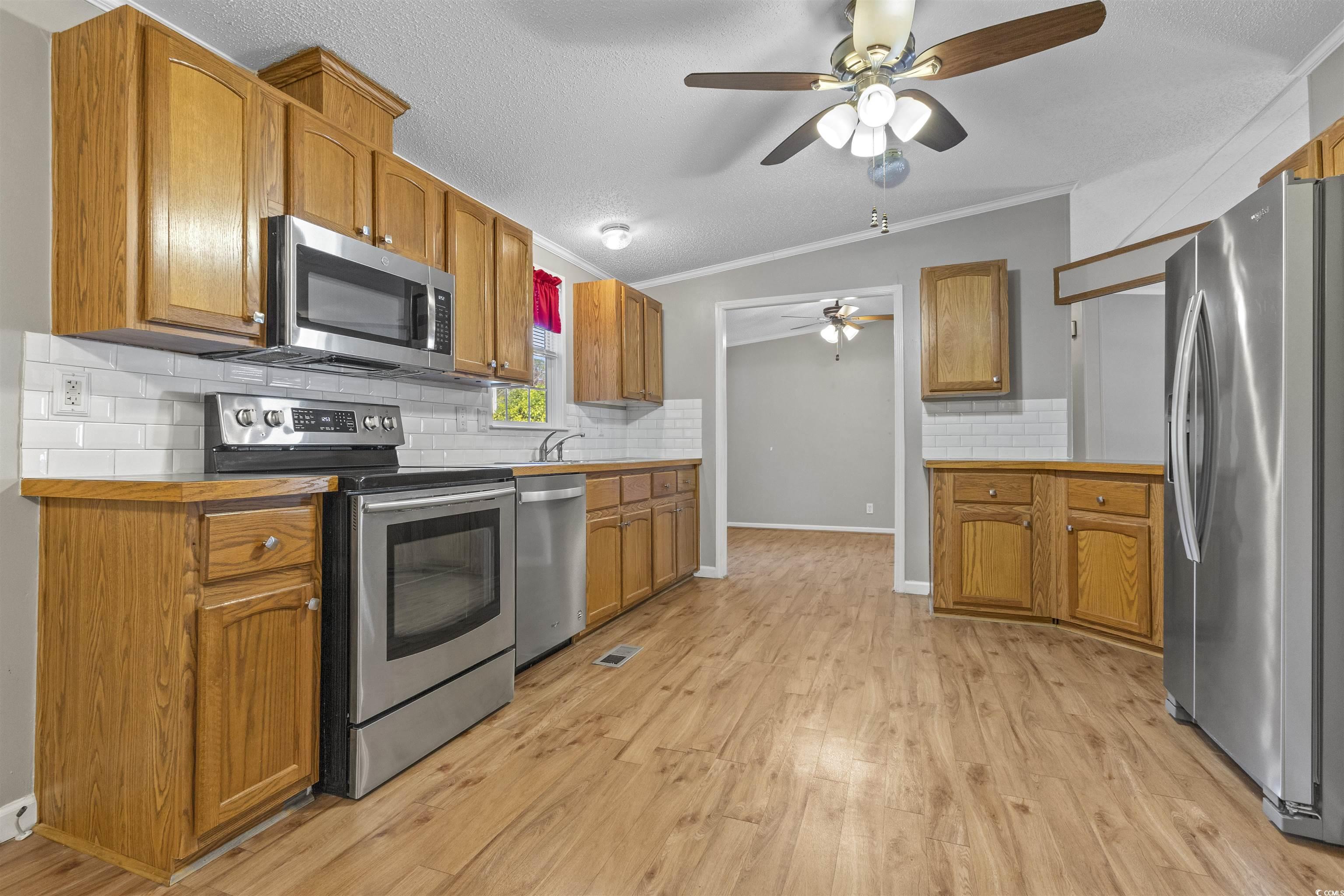 48 Talon Circle Murrells Inlet, SC 29576 - Photo 9 of 28 Kitchen featuring appliances with stainless steel finishes, crown molding, tasteful backsplash, a ceiling fan, and light wood-style floors