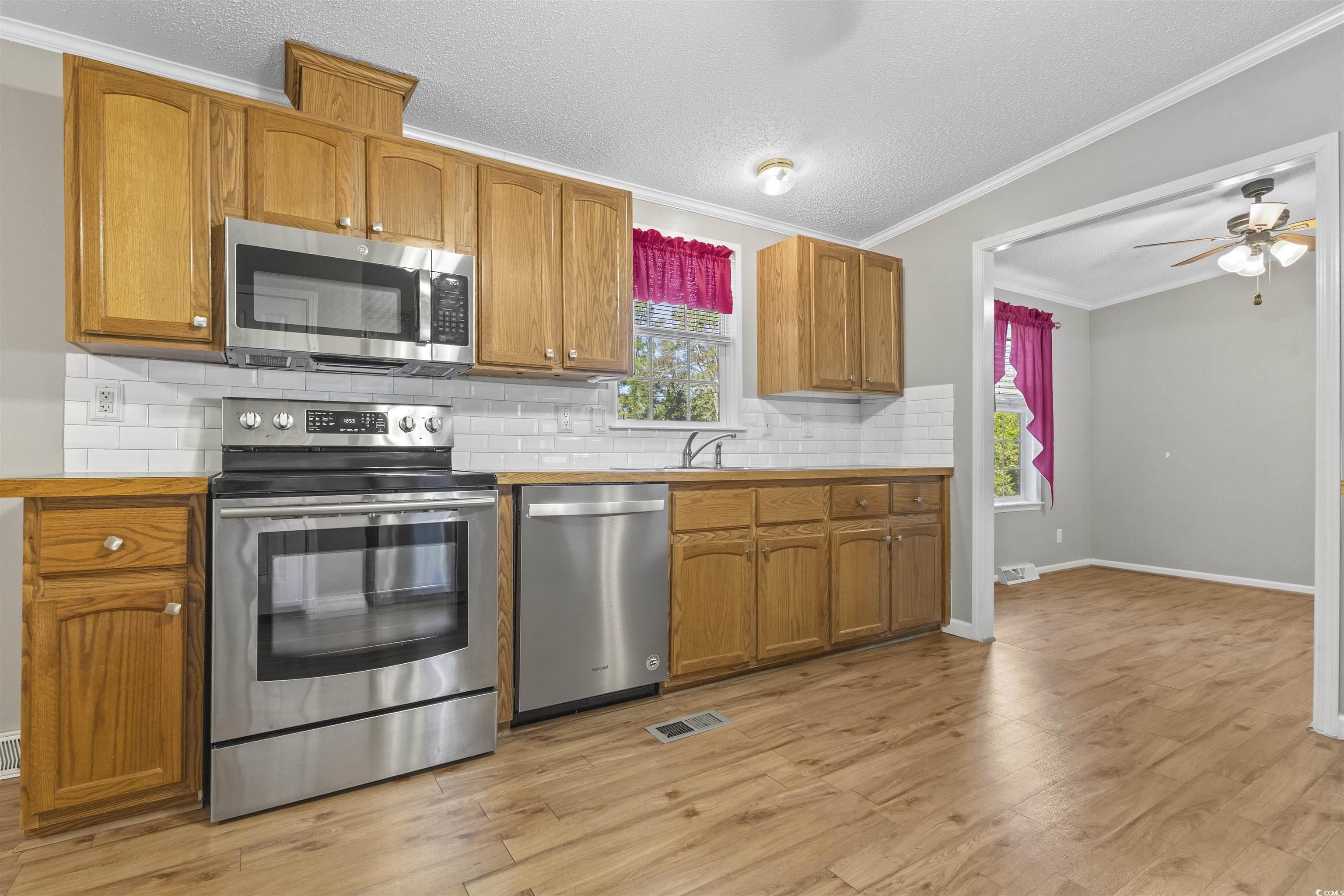 48 Talon Circle Murrells Inlet, SC 29576 - Photo 10 of 28 Kitchen featuring stainless steel appliances, ornamental molding, tasteful backsplash, a textured ceiling, and plenty of natural light