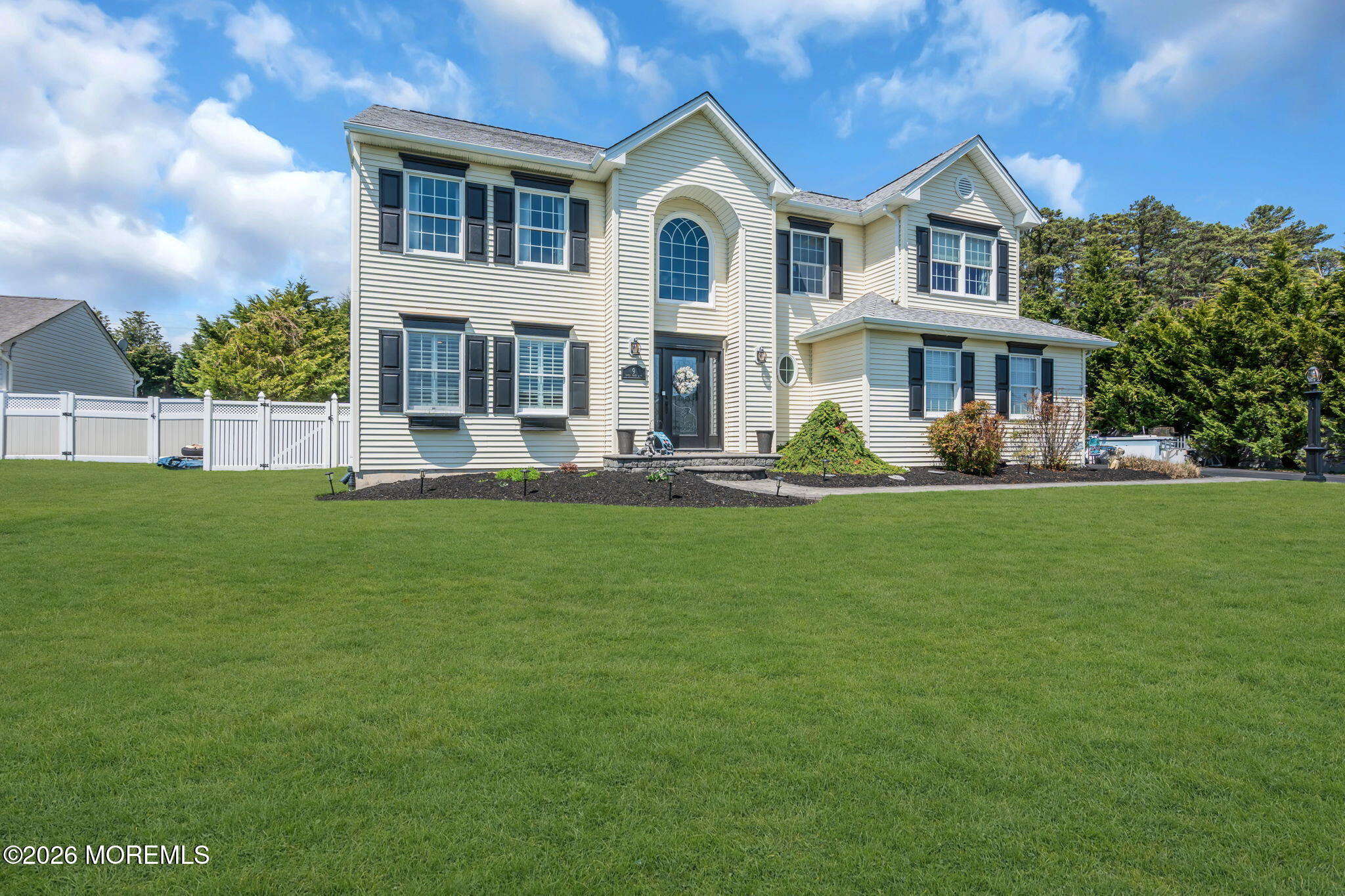 a front view of a house with a garden and trees