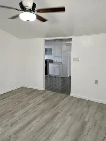 an empty room with wooden floor cabinet and windows
