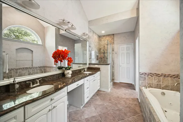 a spacious bathroom with a granite countertop double vanity sink a bathtub and shower