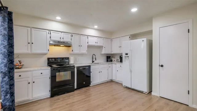 a kitchen with granite countertop a refrigerator stove top oven and sink