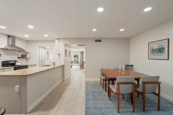a kitchen with stainless steel appliances kitchen island granite countertop a stove a sink a dining table and chairs