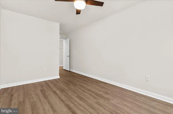 an empty room with wooden floor fan and window