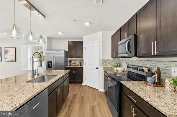 a kitchen with granite countertop kitchen island stainless steel appliances a sink stove top oven and refrigerator